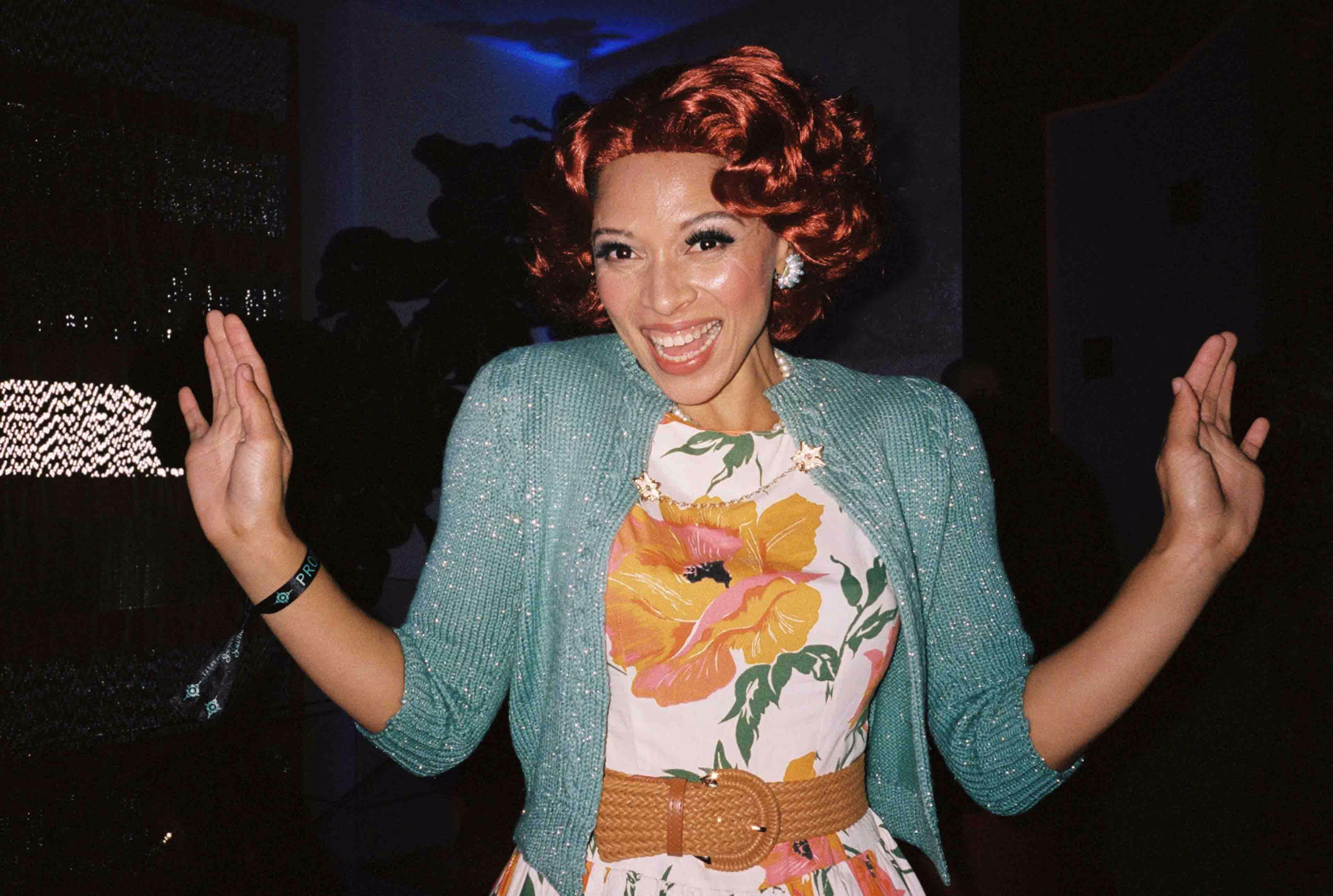 A woman with red hair wearing a floral dress.