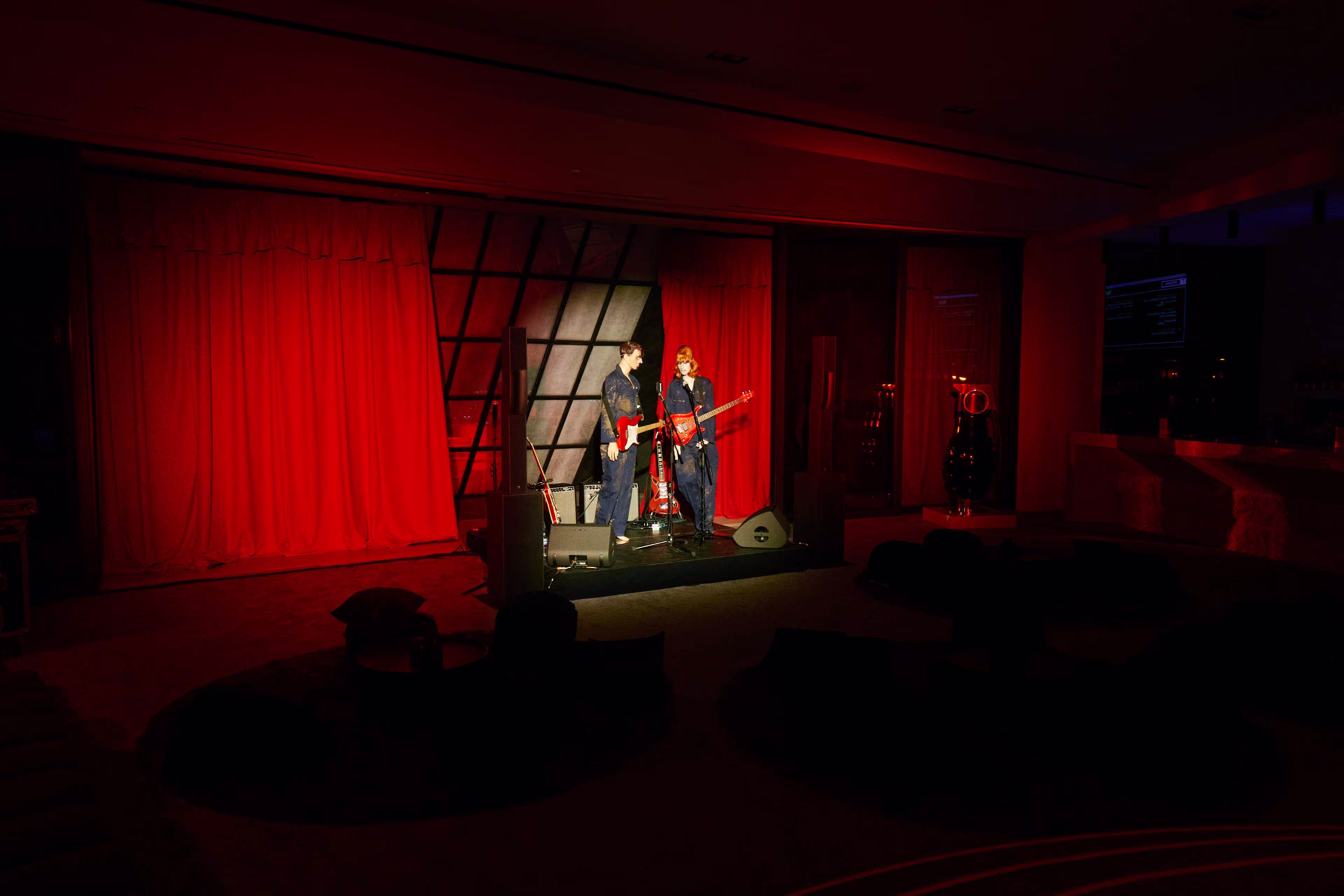 A man standing on a stage in front of a red curtain.