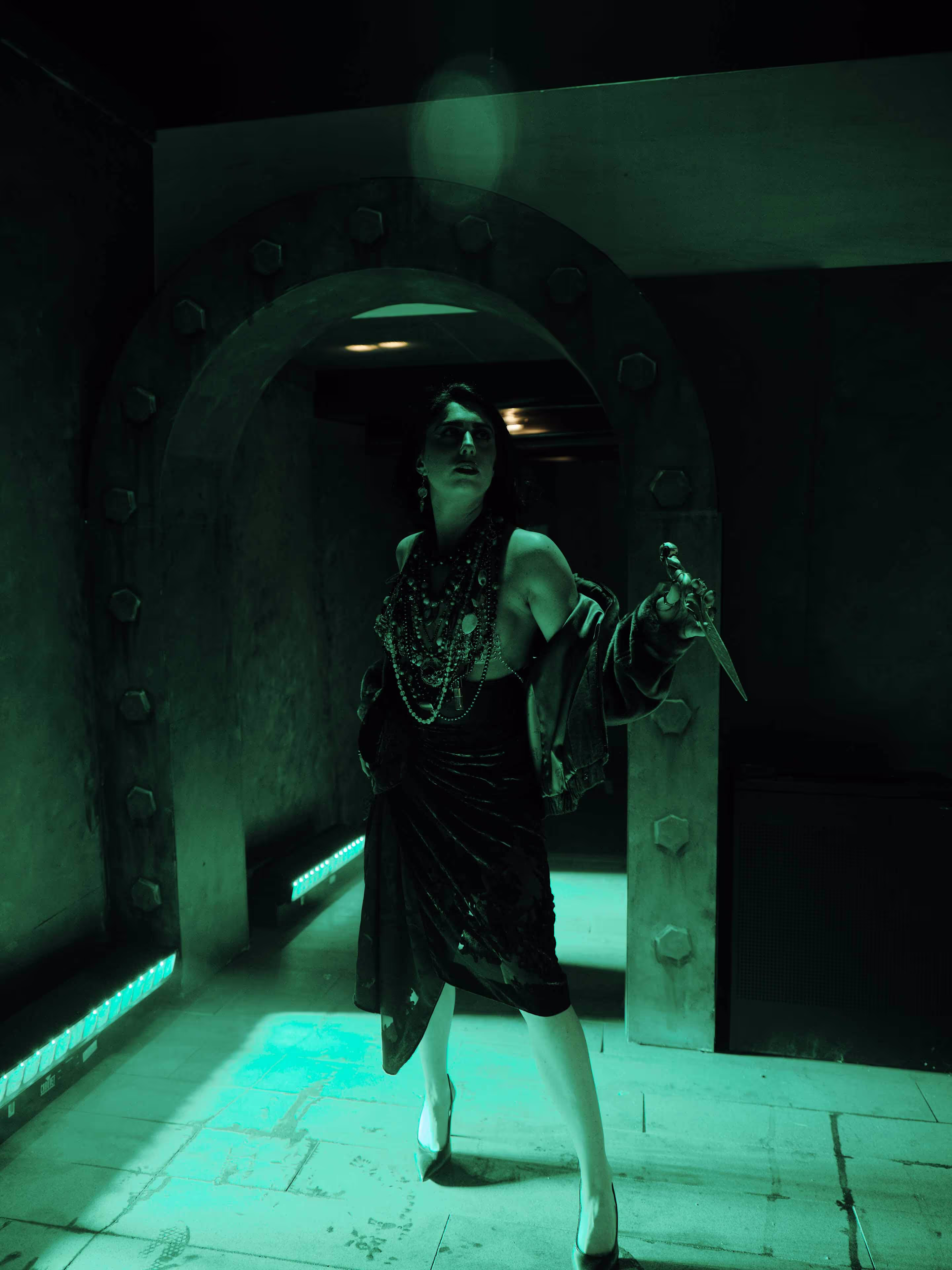 A woman in a black dress is dancing in a dimly lit room.