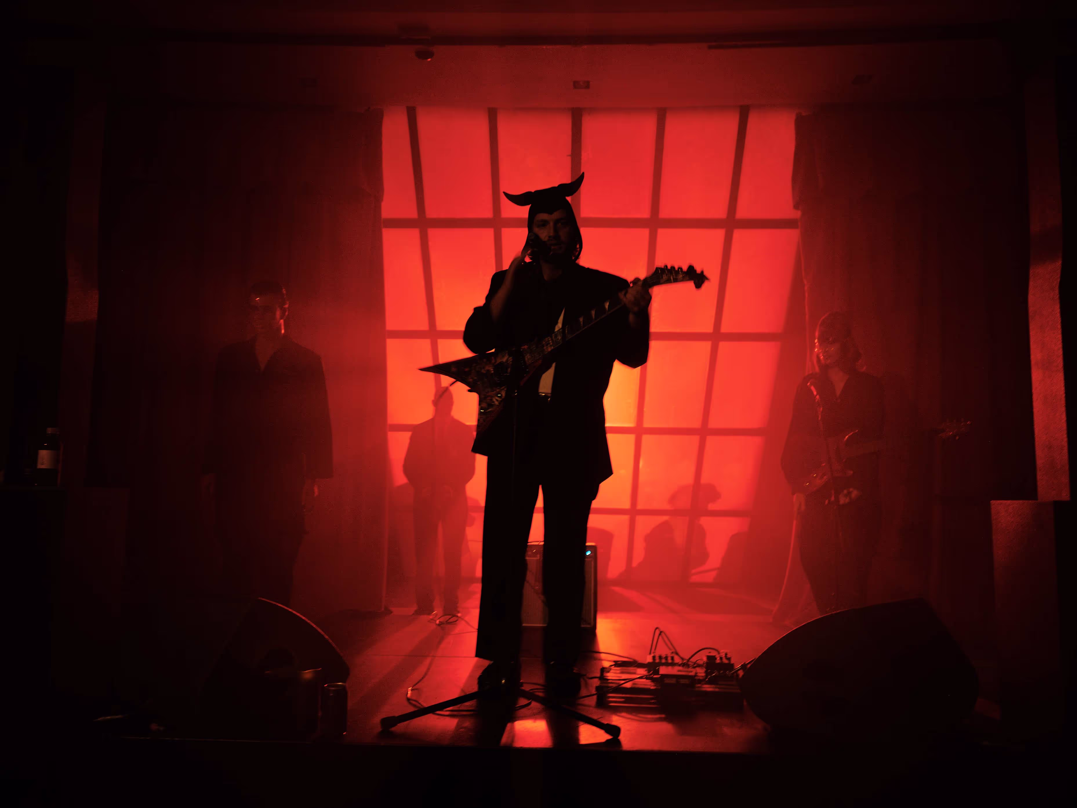 A man with a guitar standing in front of a window.