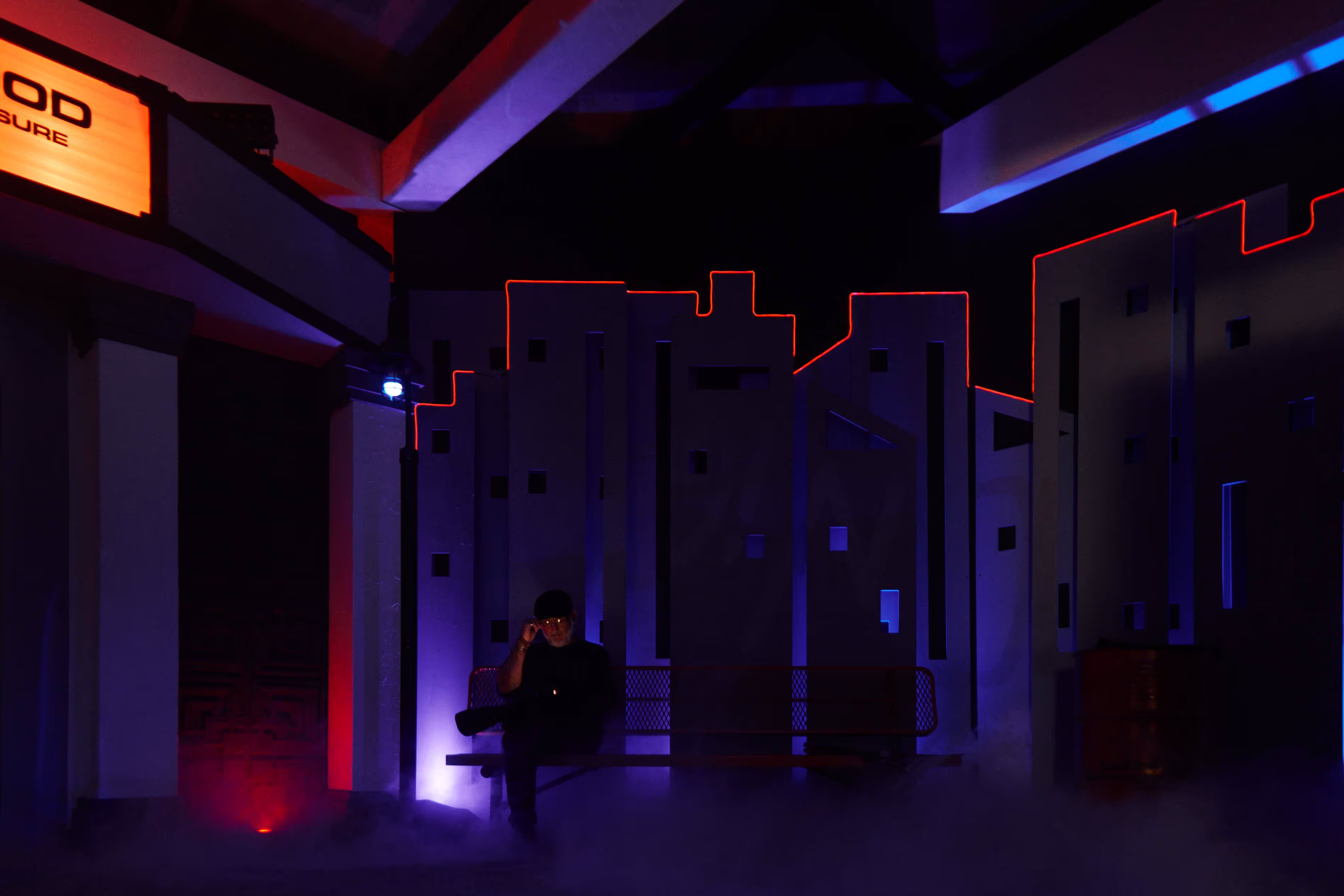 A person standing in a dark room with a neon light.