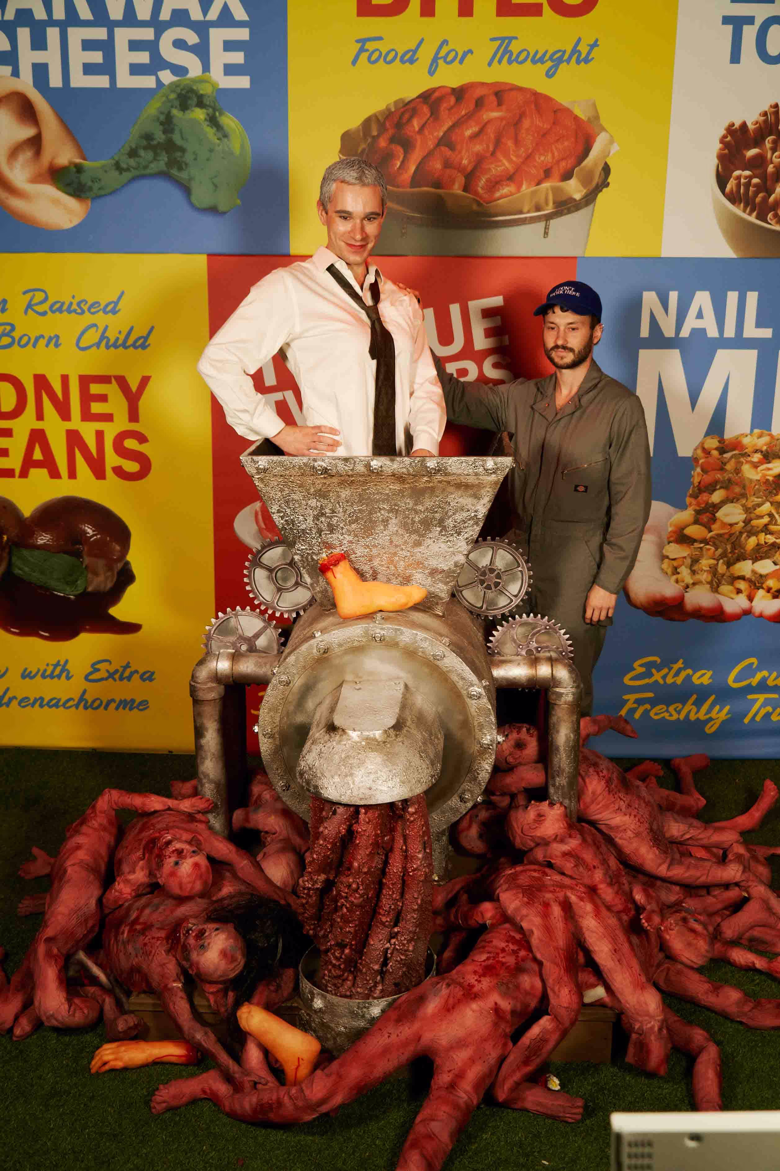 Two men standing next to a pile of food.