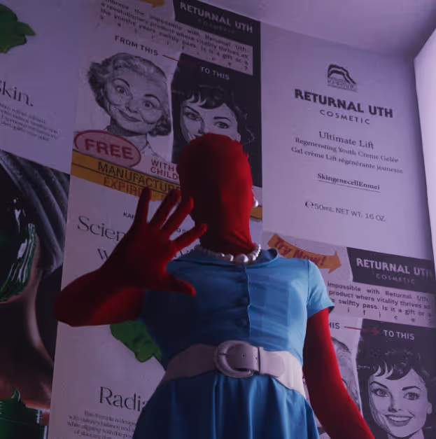 A woman in a blue dress standing in front of a wall with advertisements on it.
