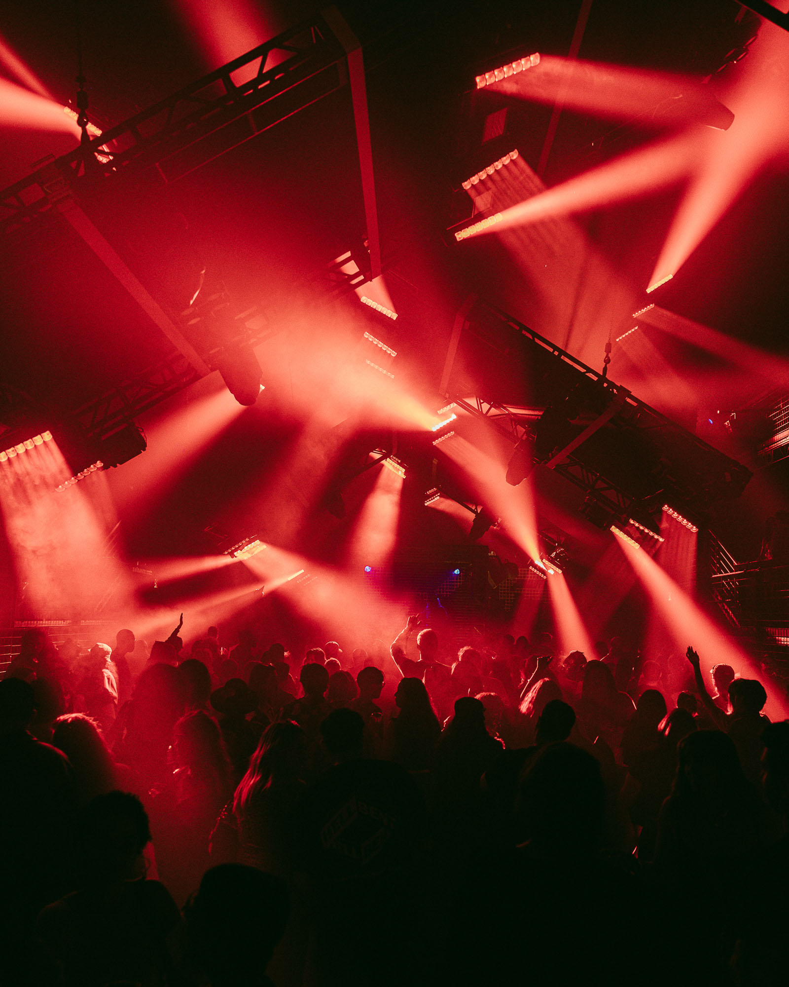 A large crowd of people at a rave with red lights 