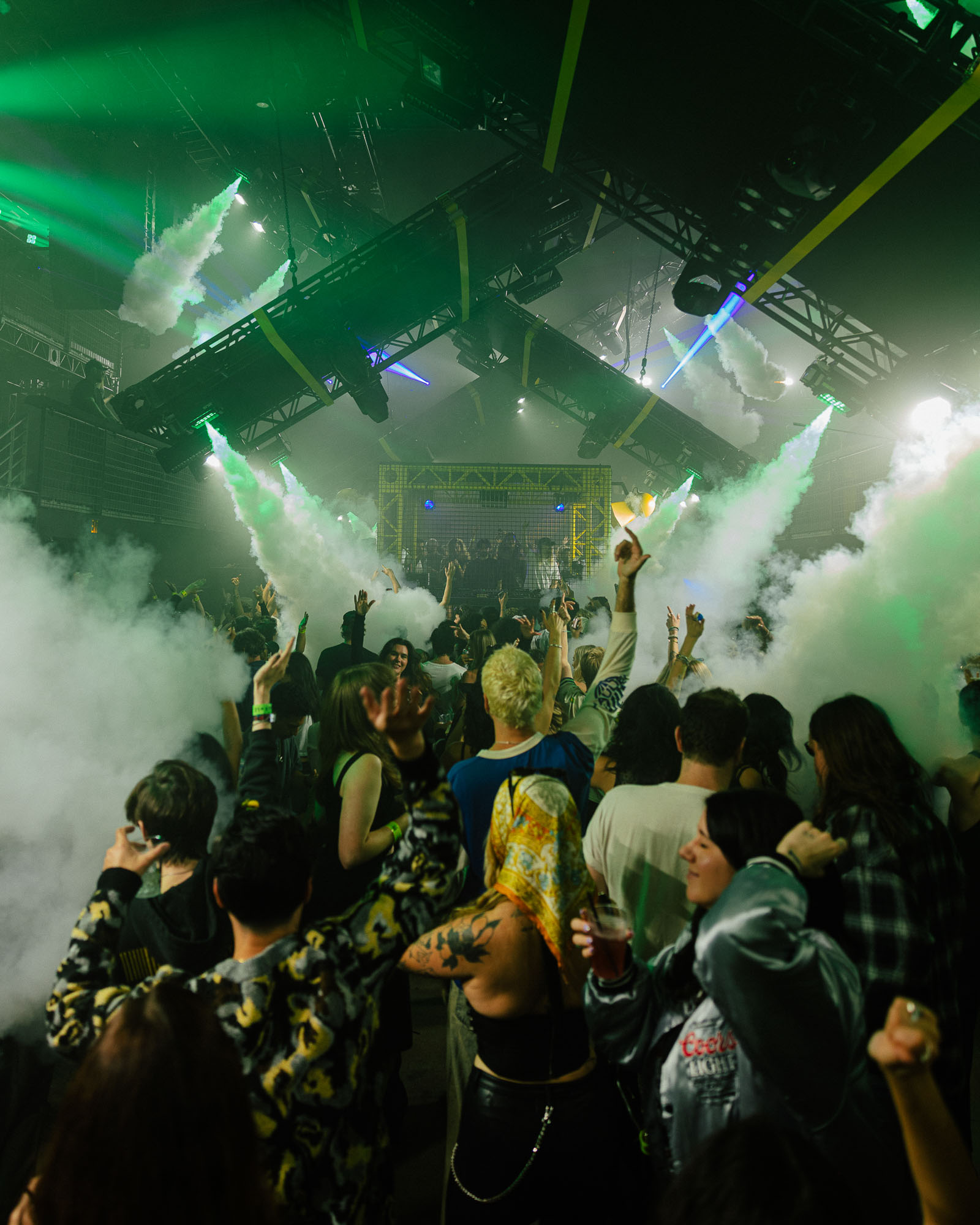 A group of people standing around a rave filled with smoke.