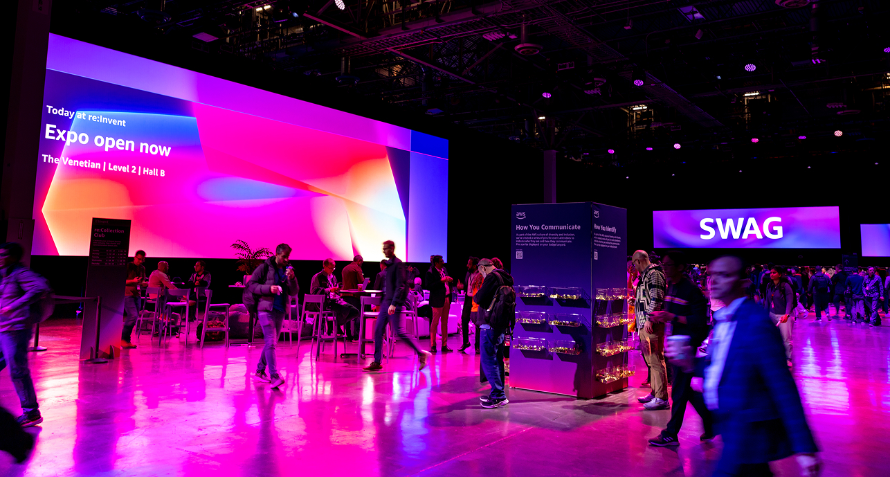 Indoor expo hall with people walking and sitting, vibrant pink and purple lighting, large screens displaying 'Expo open now' and 'SWAG'.