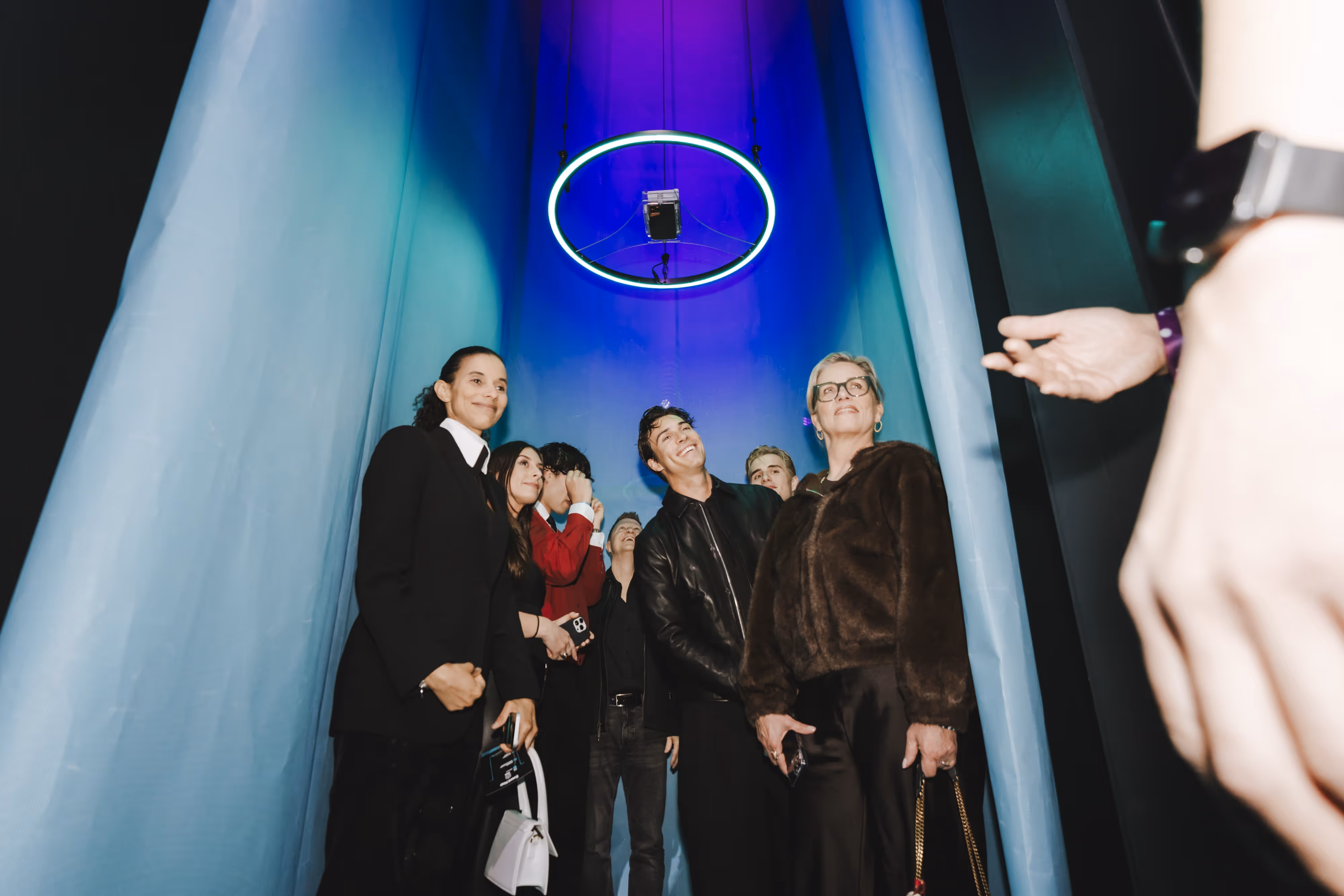 A group of people standing in front of a blue wall.