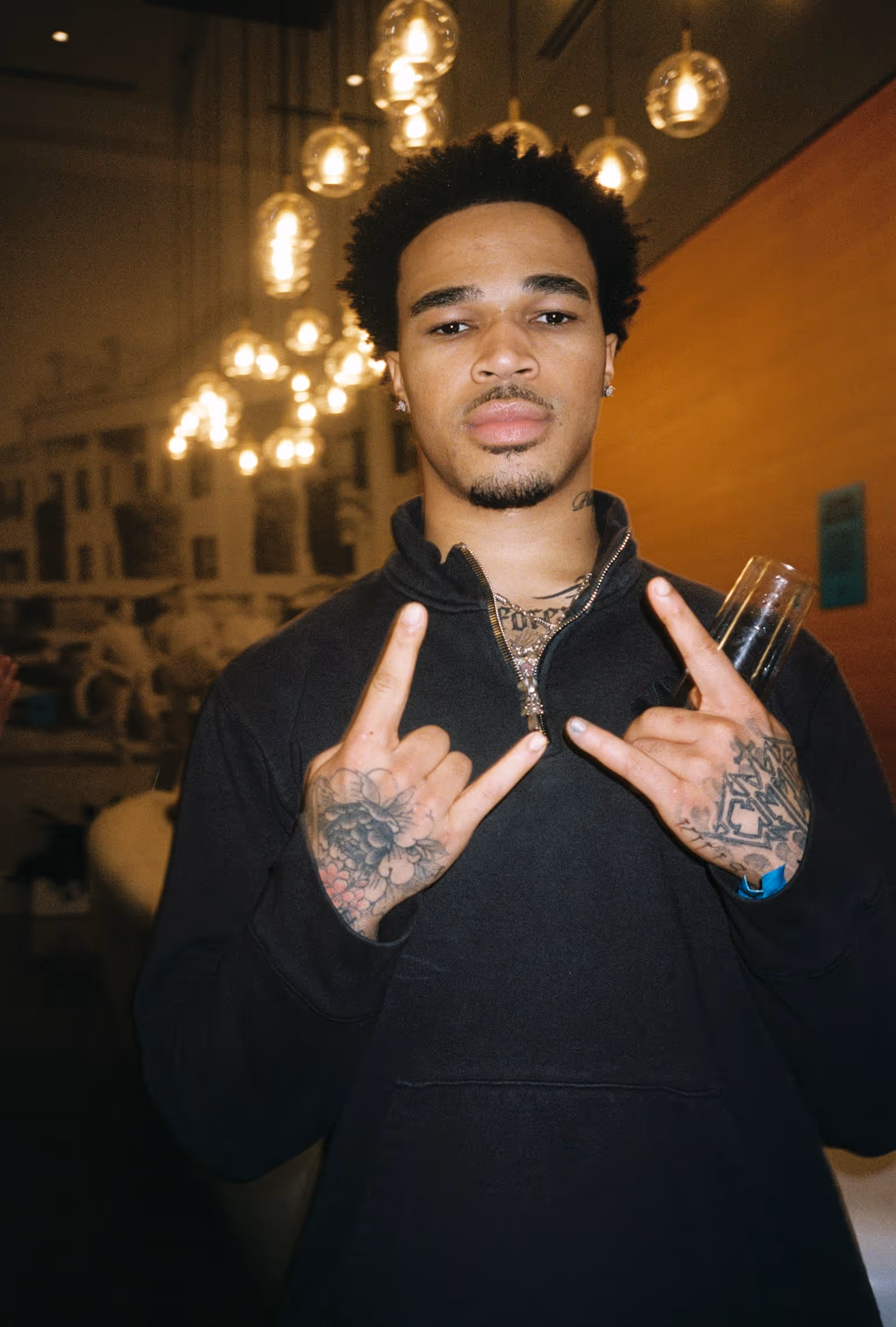 A man with tattoos holding up two fingers.