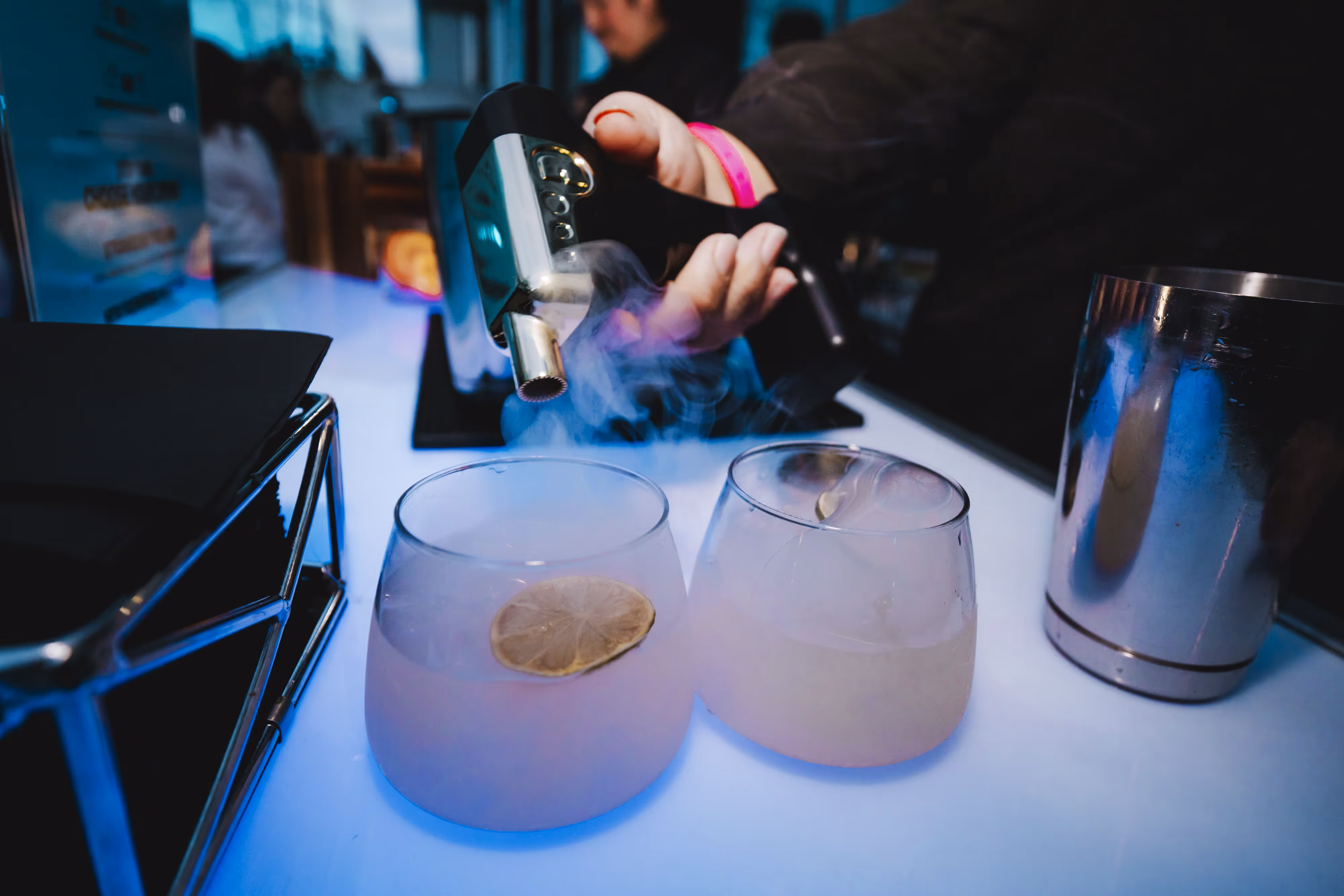 A person pouring a drink into two glasses.