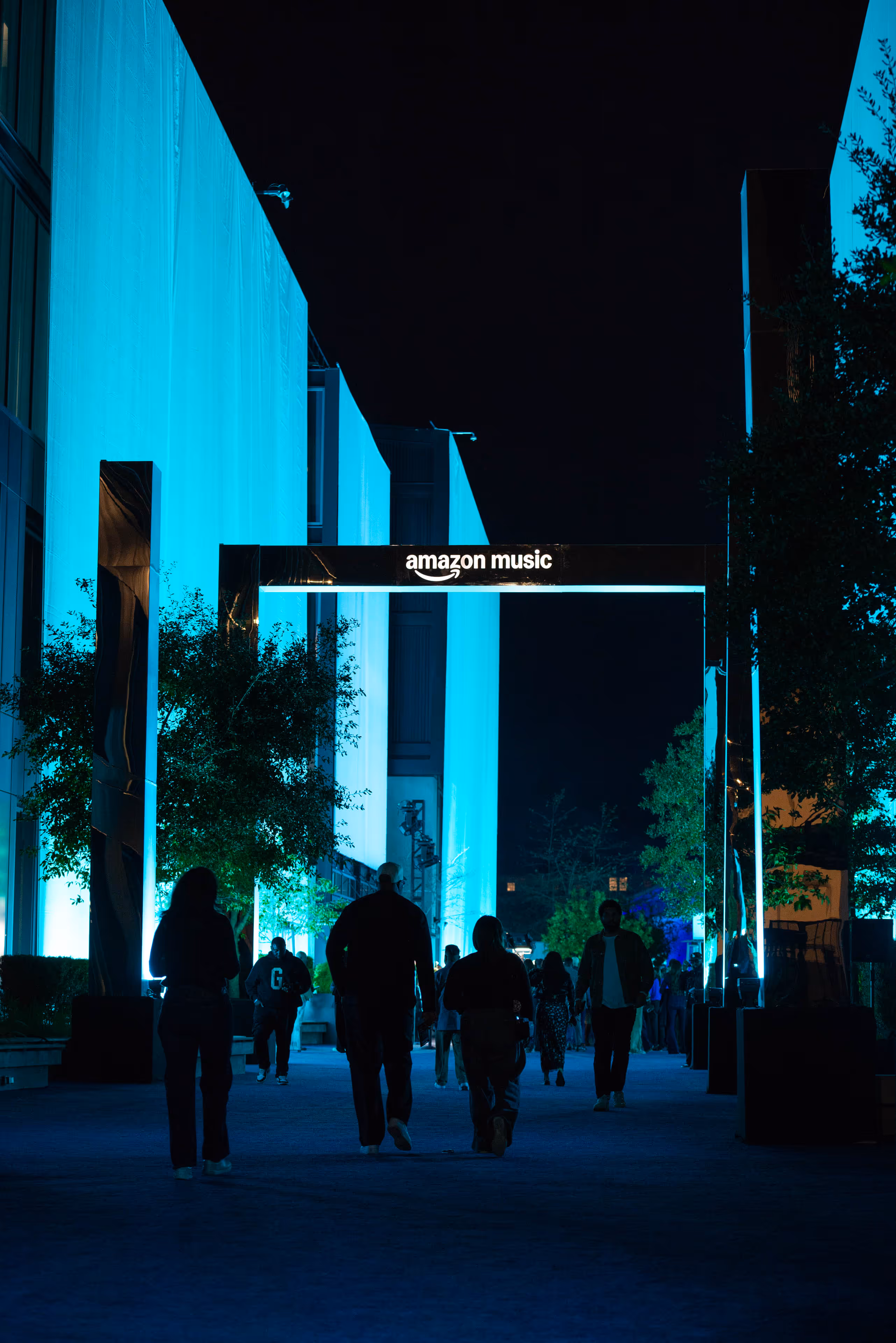 A group of people walking down a street at night.