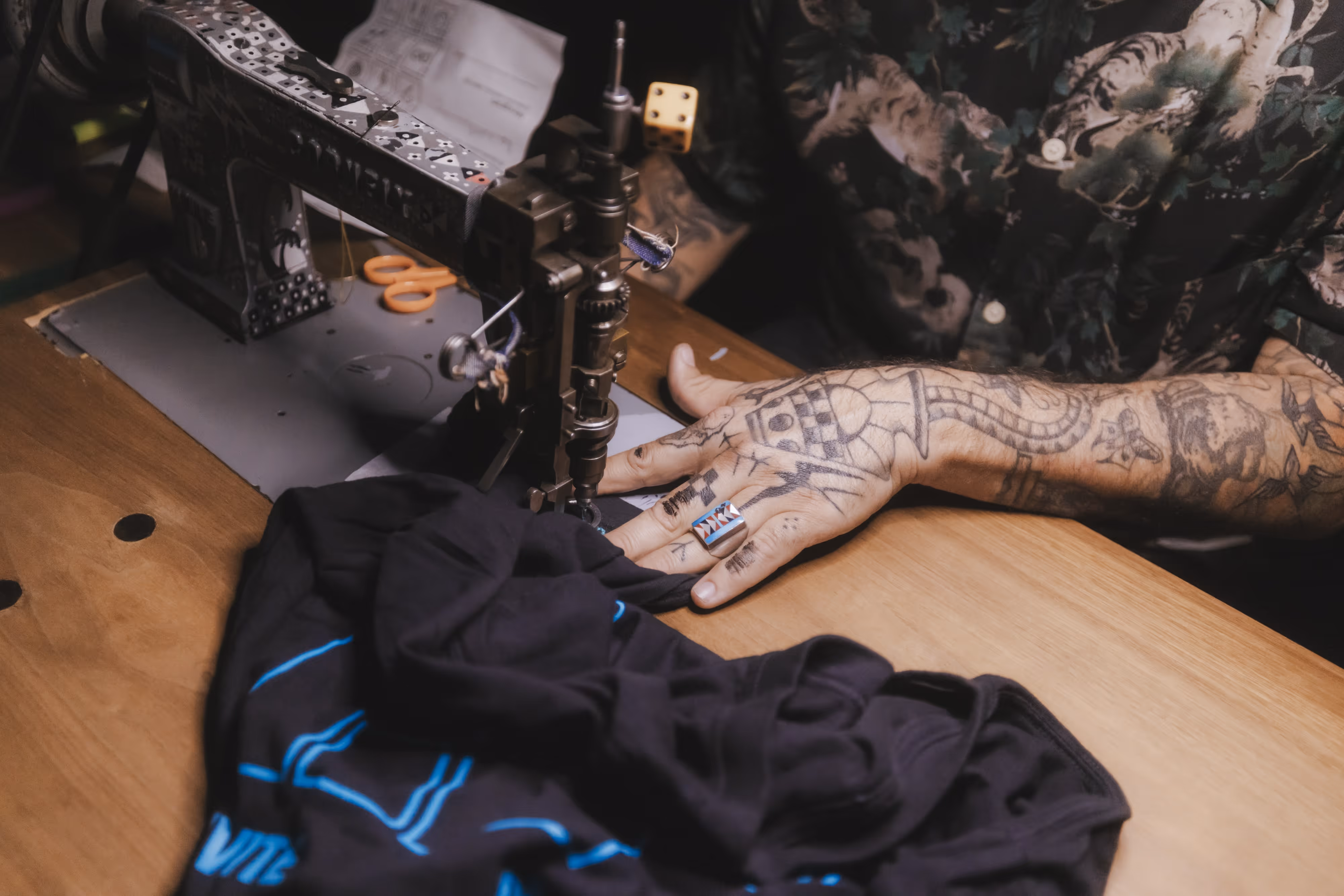 A tattooed man working on a sewing machine.