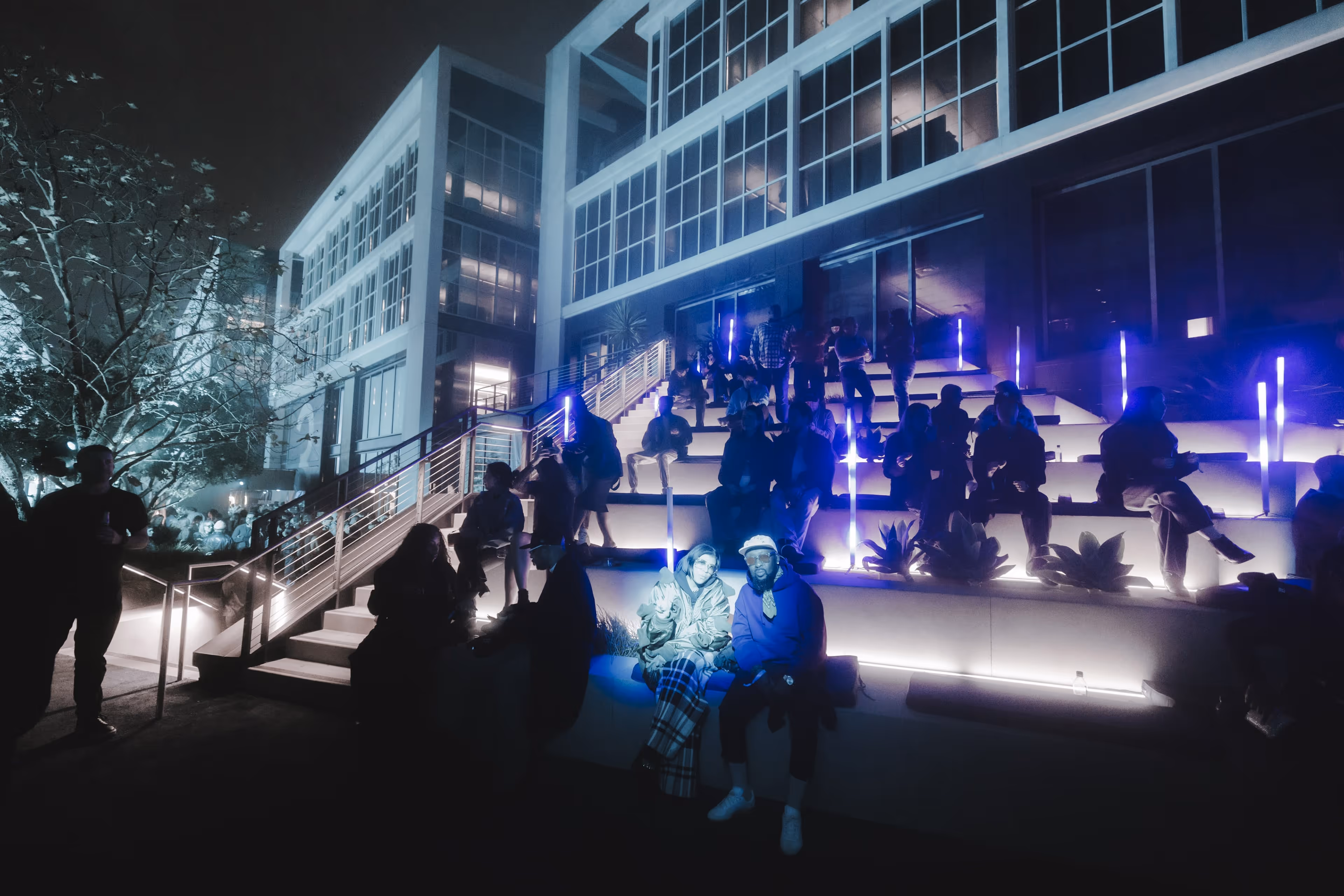 A group of people standing around a building at night.