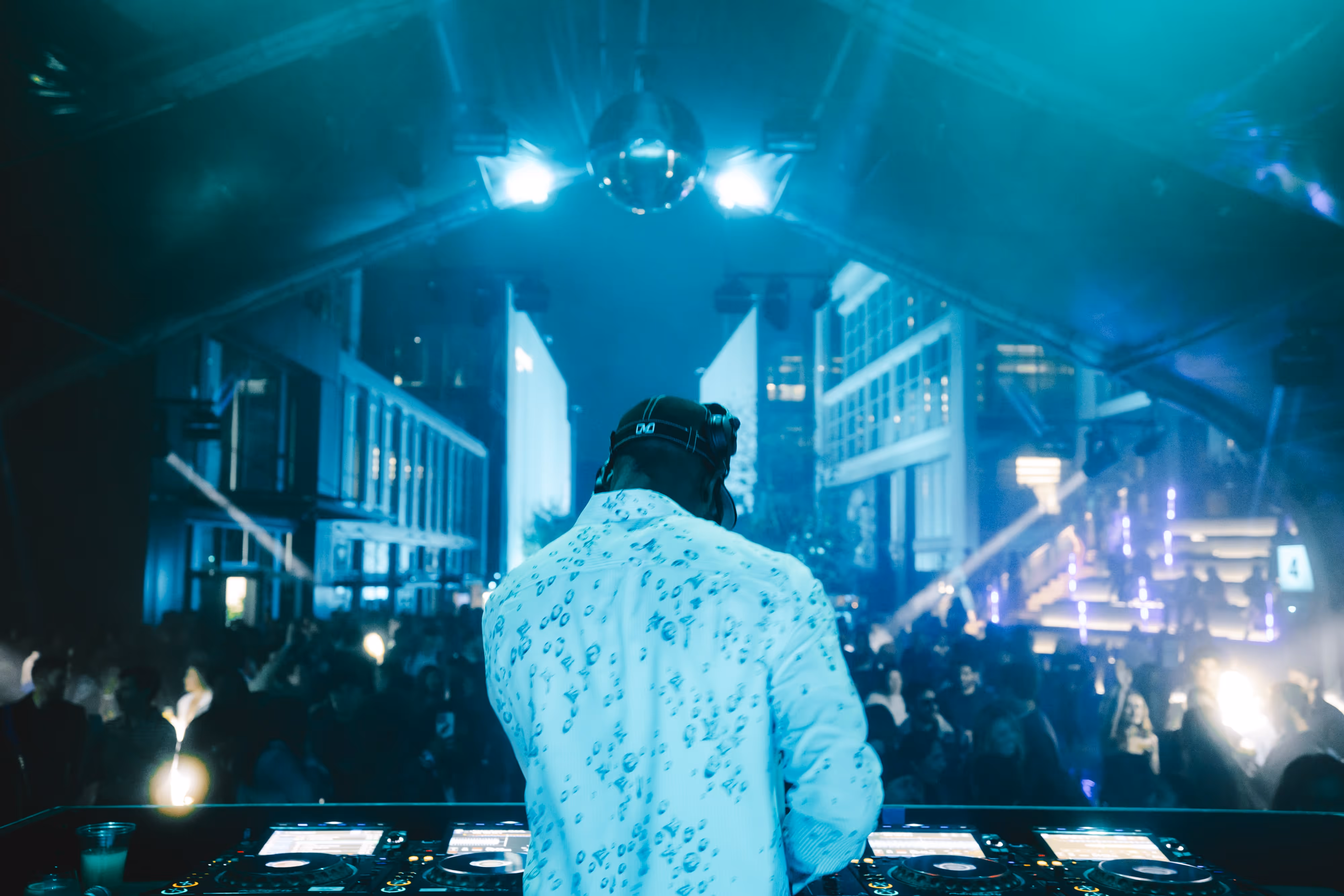 A dj mixing in front of a crowd of people.