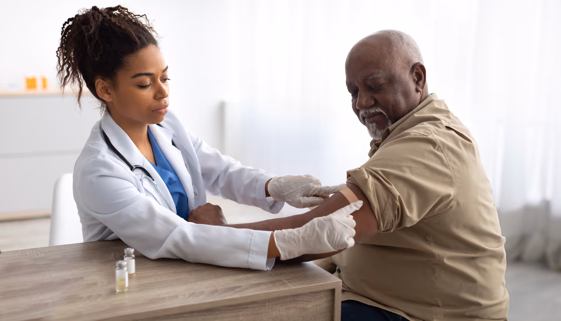 A doctor applying a bandage to her patient inside of a clinic after a vaccine injection.