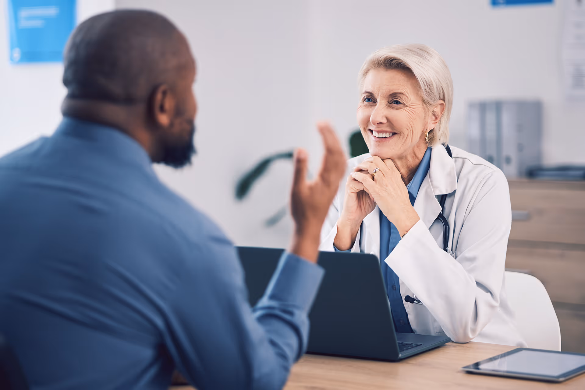 A man and female older doctor talking inside an office.