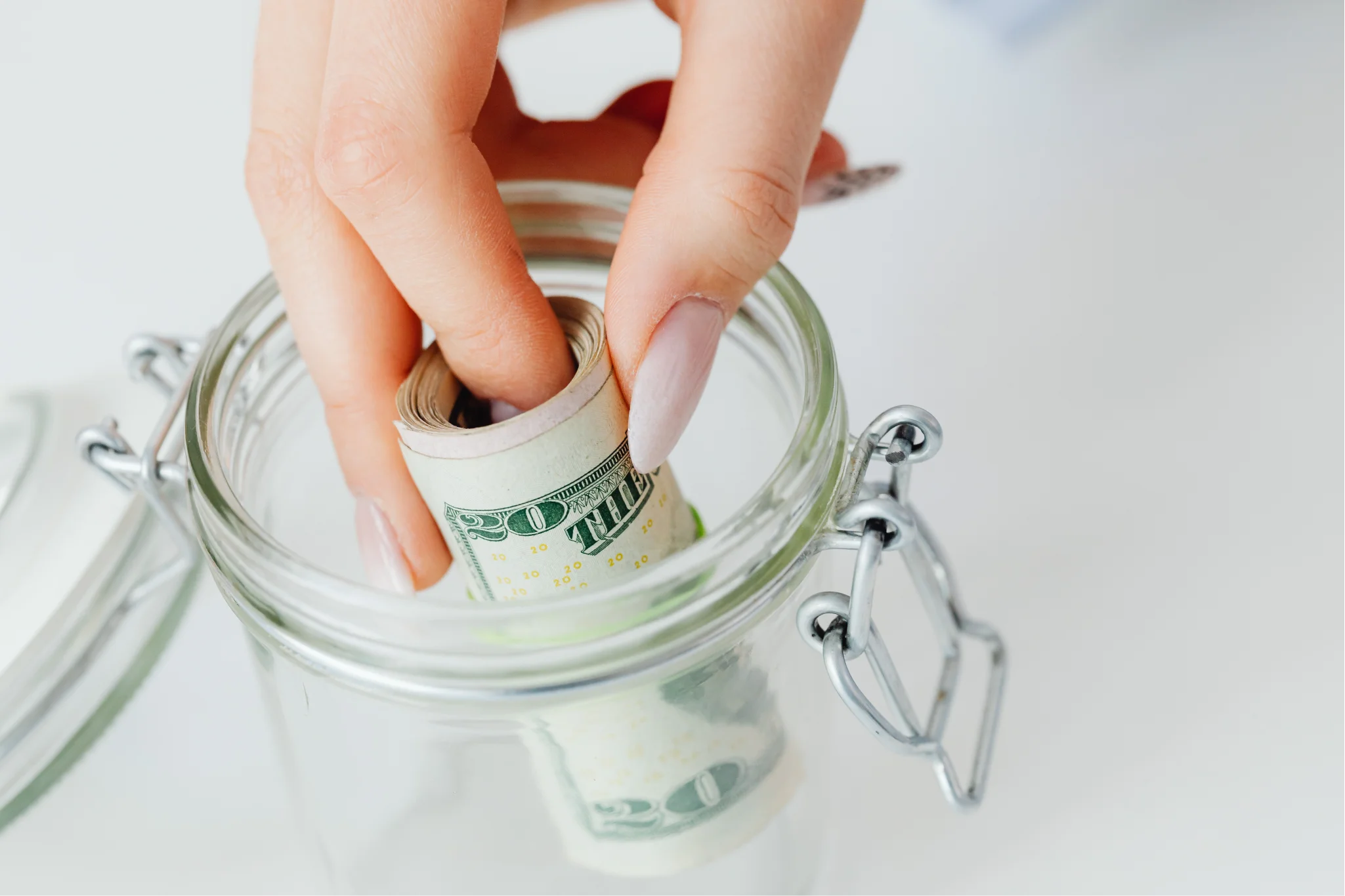 A hand putting money into a jar