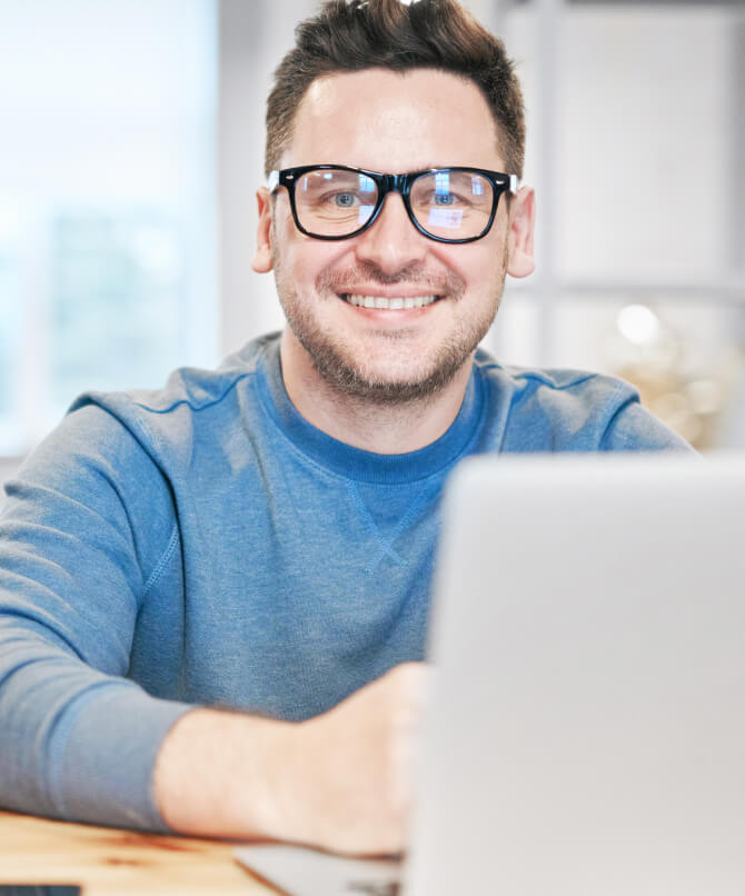 Man with glasses on Macbook Pro