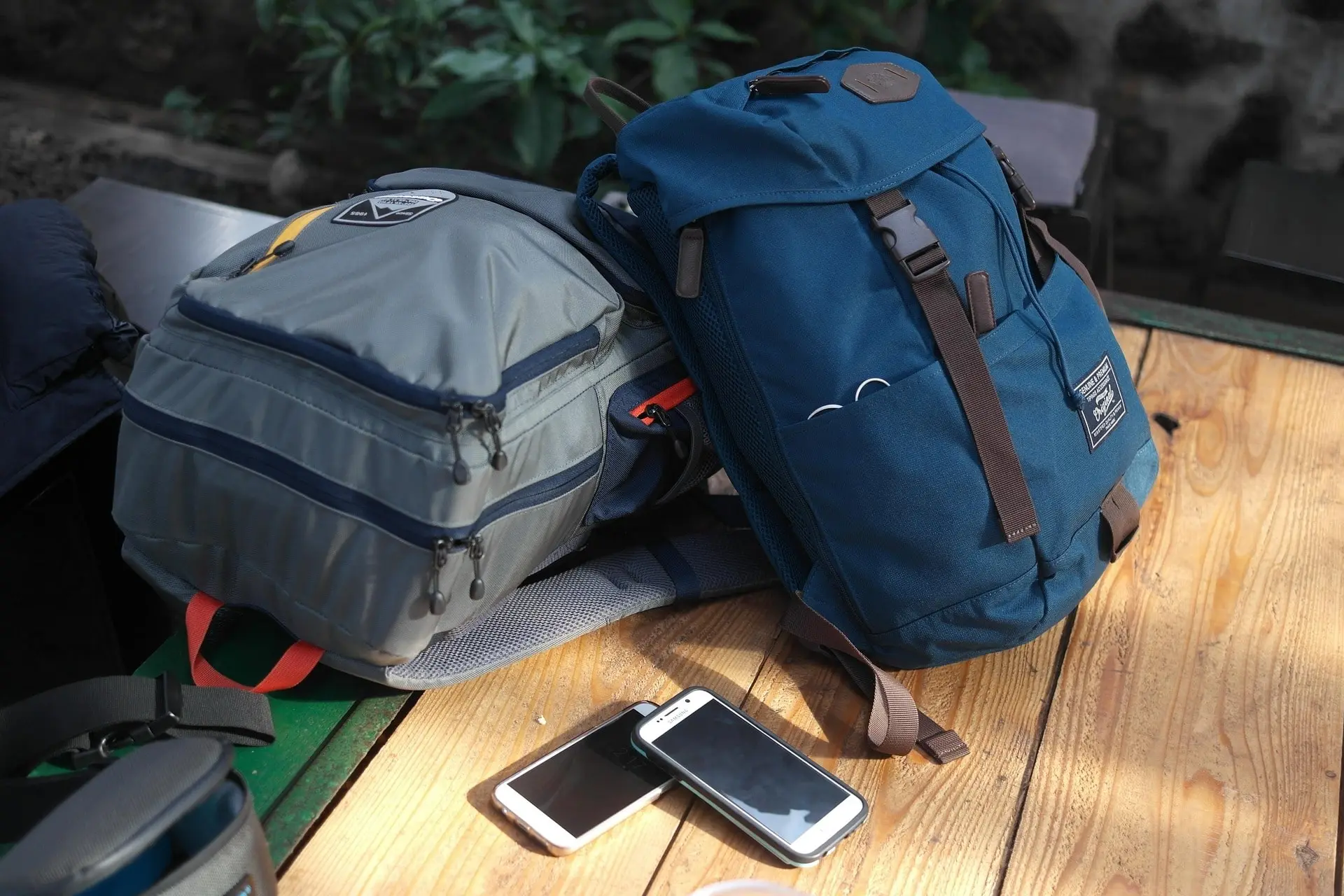 Two smartphones are placed on the table next to the bags, with one slightly overlapping the other.
