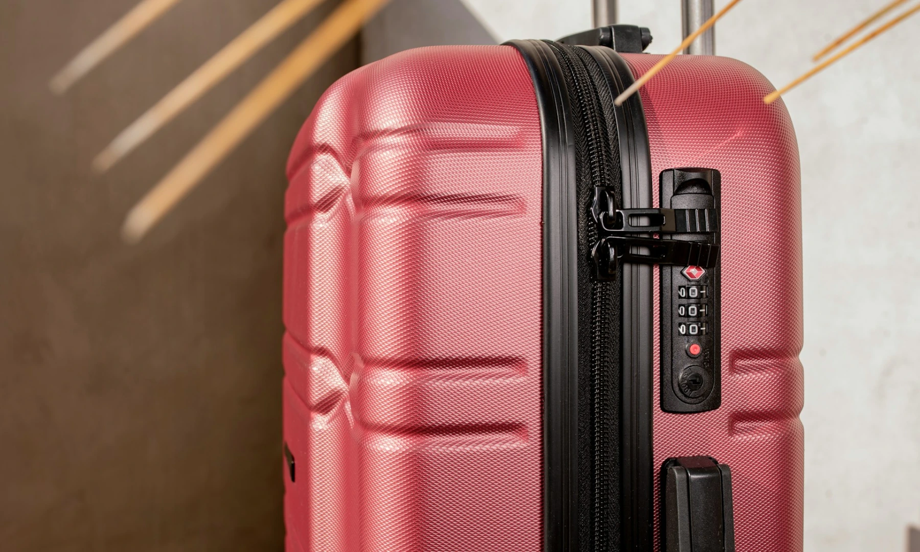 A pink, carry-on suitcase with a built-in locking system.