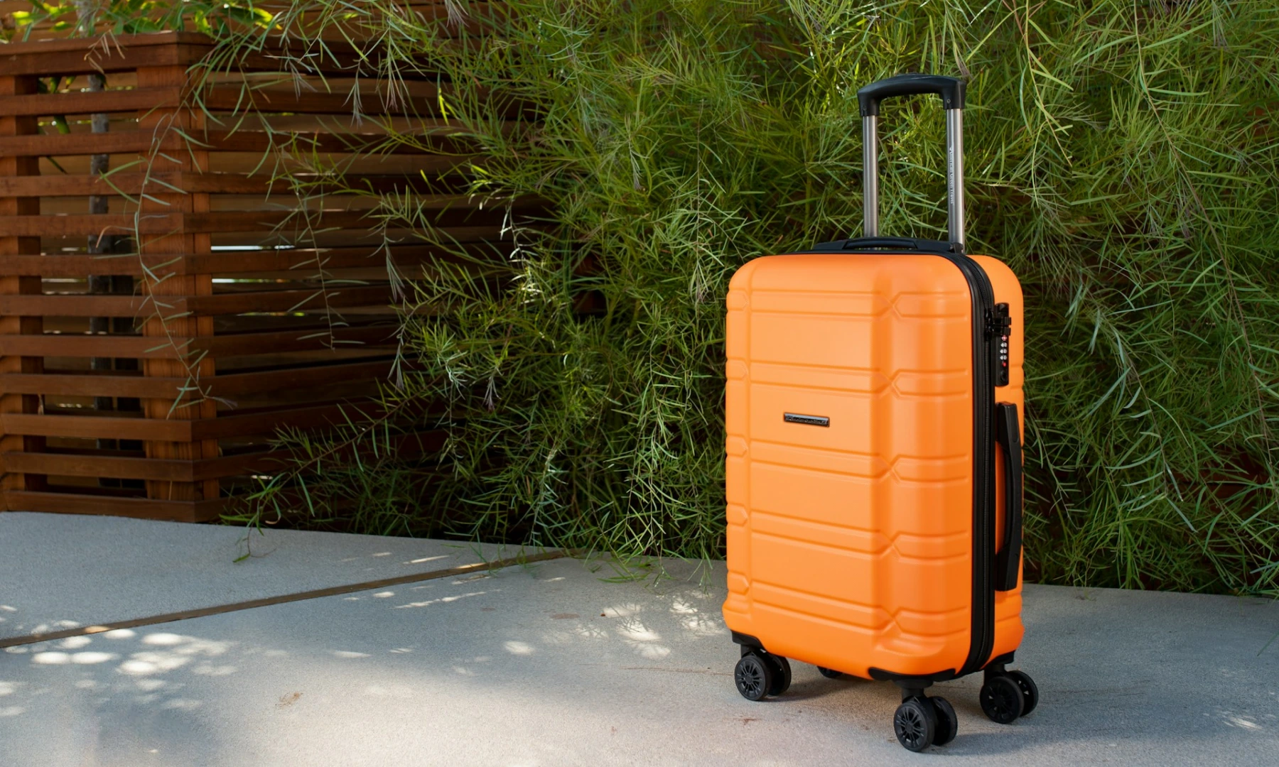A rigid, bright orange suitcase for international travel.