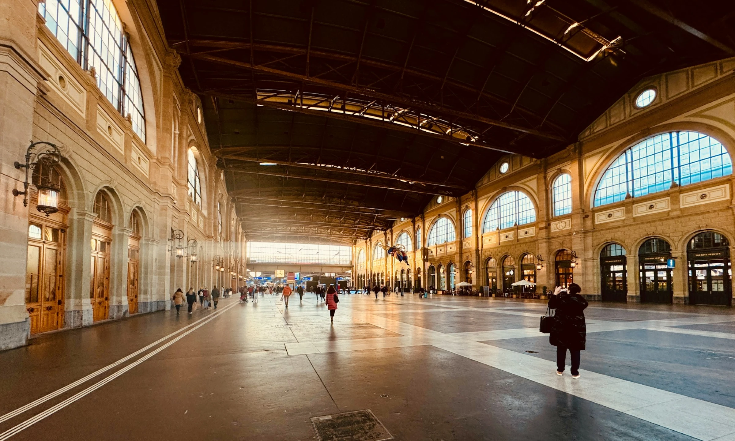 Wide-angle interior shot of Zurich's main train station, highlighting its grandiose architecture with high arched ceilings, classical columns, and expansive hallways. Zurich Hauptbahnhof is where you’ll start your layover in Zurich.