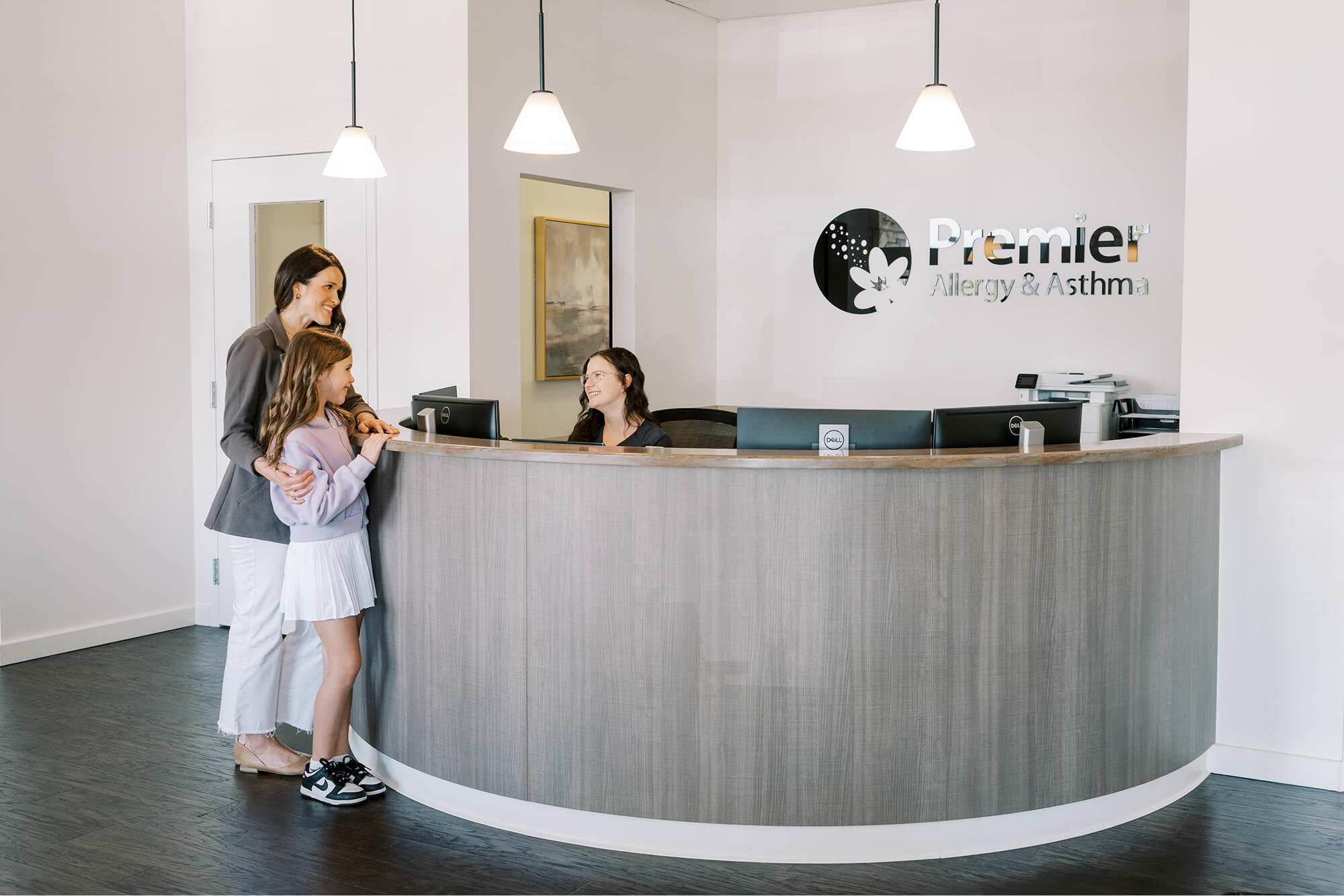 A woman and a little girl standing in front of a reception desk.