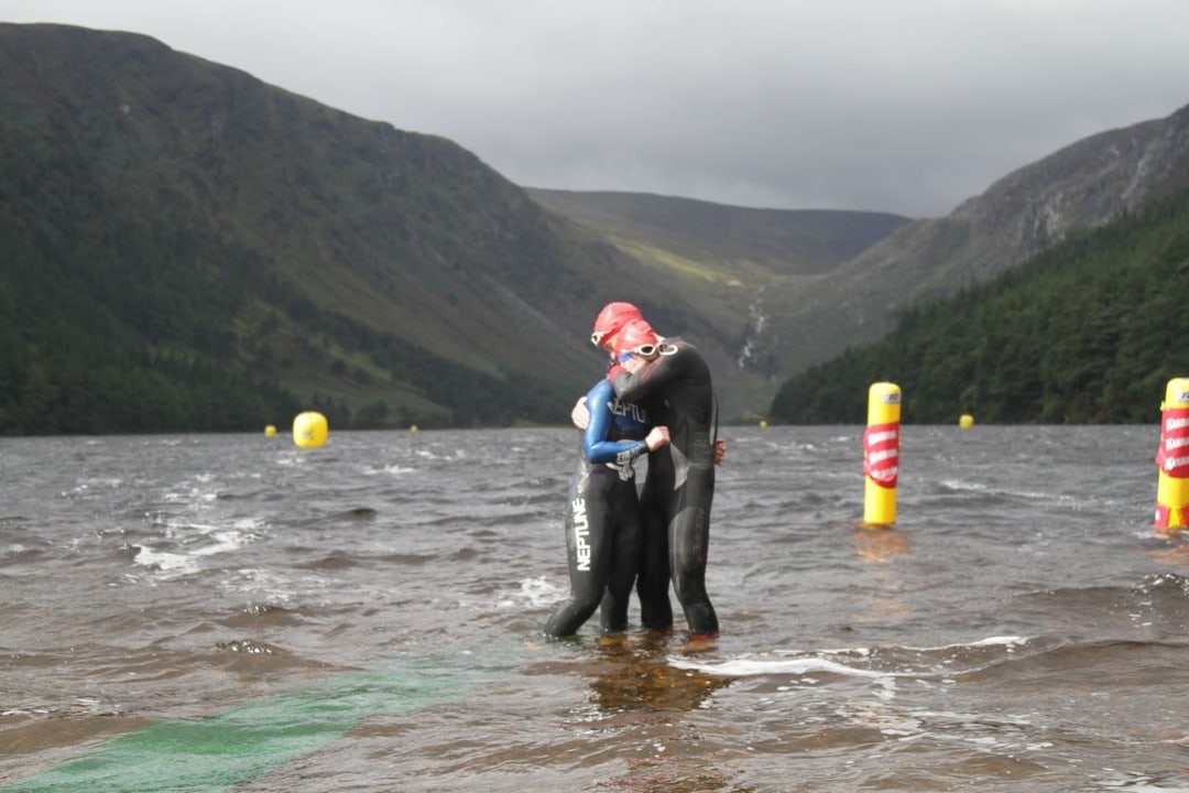 Two Open water swimmers embracing in the lake after completing their races event with Open Water Swimmer