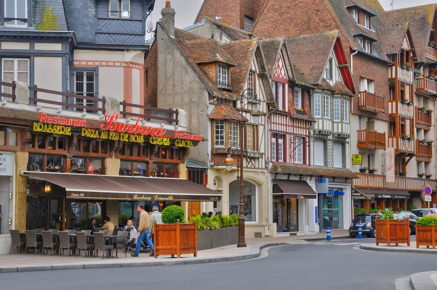 Façades à colombages colorées et terrasse de restaurant à Deauville, typiques de l’architecture normande.