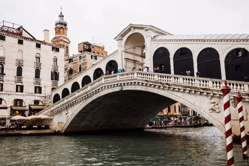 Le célèbre pont du Rialto à Venise vu depuis le canal, avec des passants et bâtiments anciens