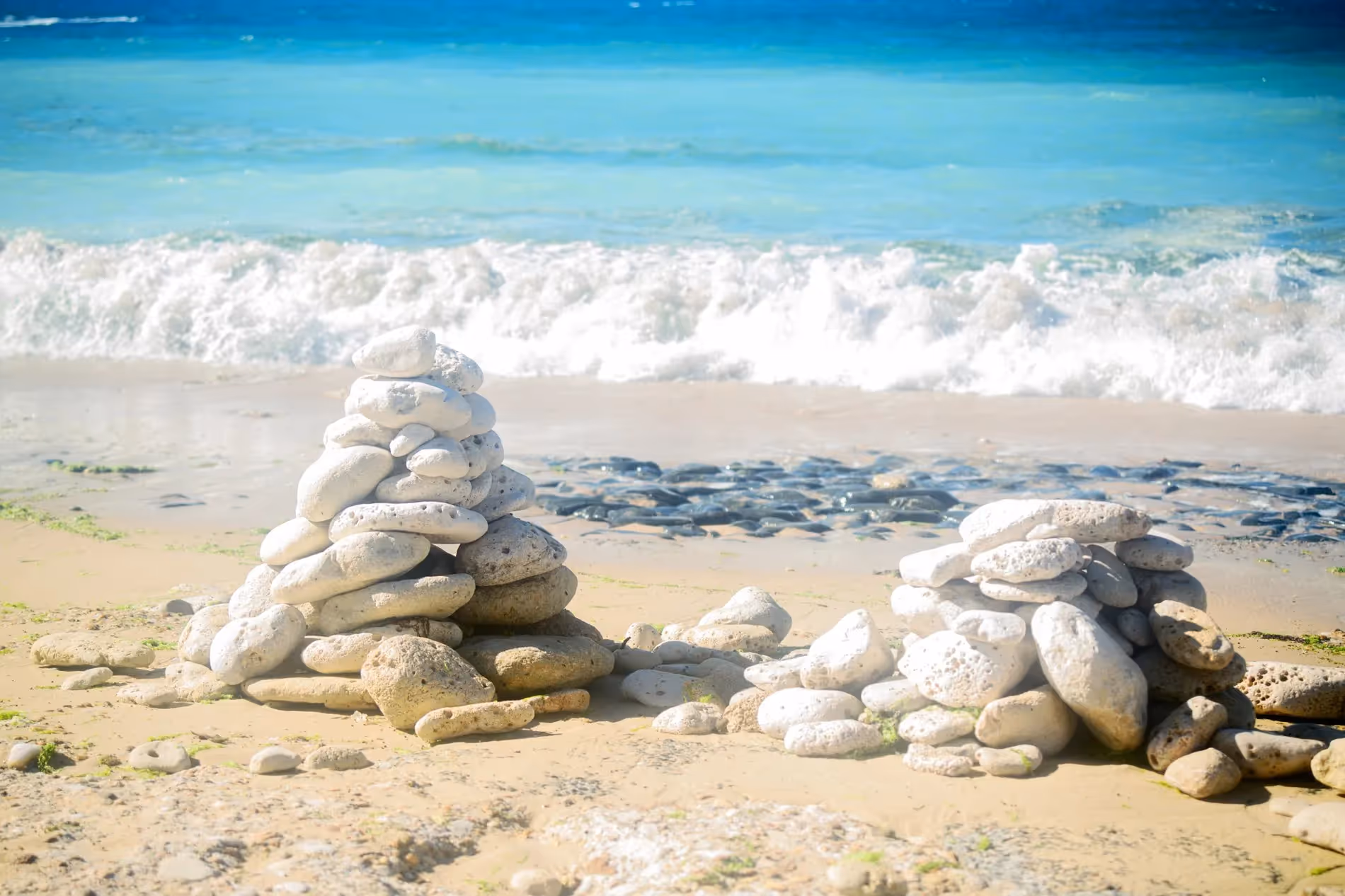 Deux cairns de galets blancs posés sur une plage de sable fin, face à l’océan Atlantique, sur l’île de Ré.