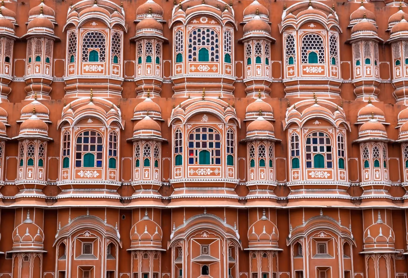 Façade rose ornée du Palais des Vents à Jaipur, avec ses nombreuses fenêtres décorées typiques de l’architecture rajput.