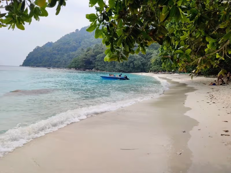 Plage de Turtle Beach avec sable blanc et mer calme, encadrée par une végétation dense sur Pulau Besar.