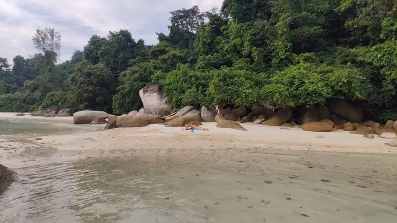 Petite plage isolée bordée de gros rochers et entourée de jungle tropicale aux îles Perhentian.