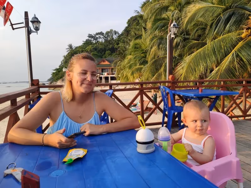 Moment en famille autour d’une table avec vue sur la plage et les cocotiers à Perhentian Besar.
