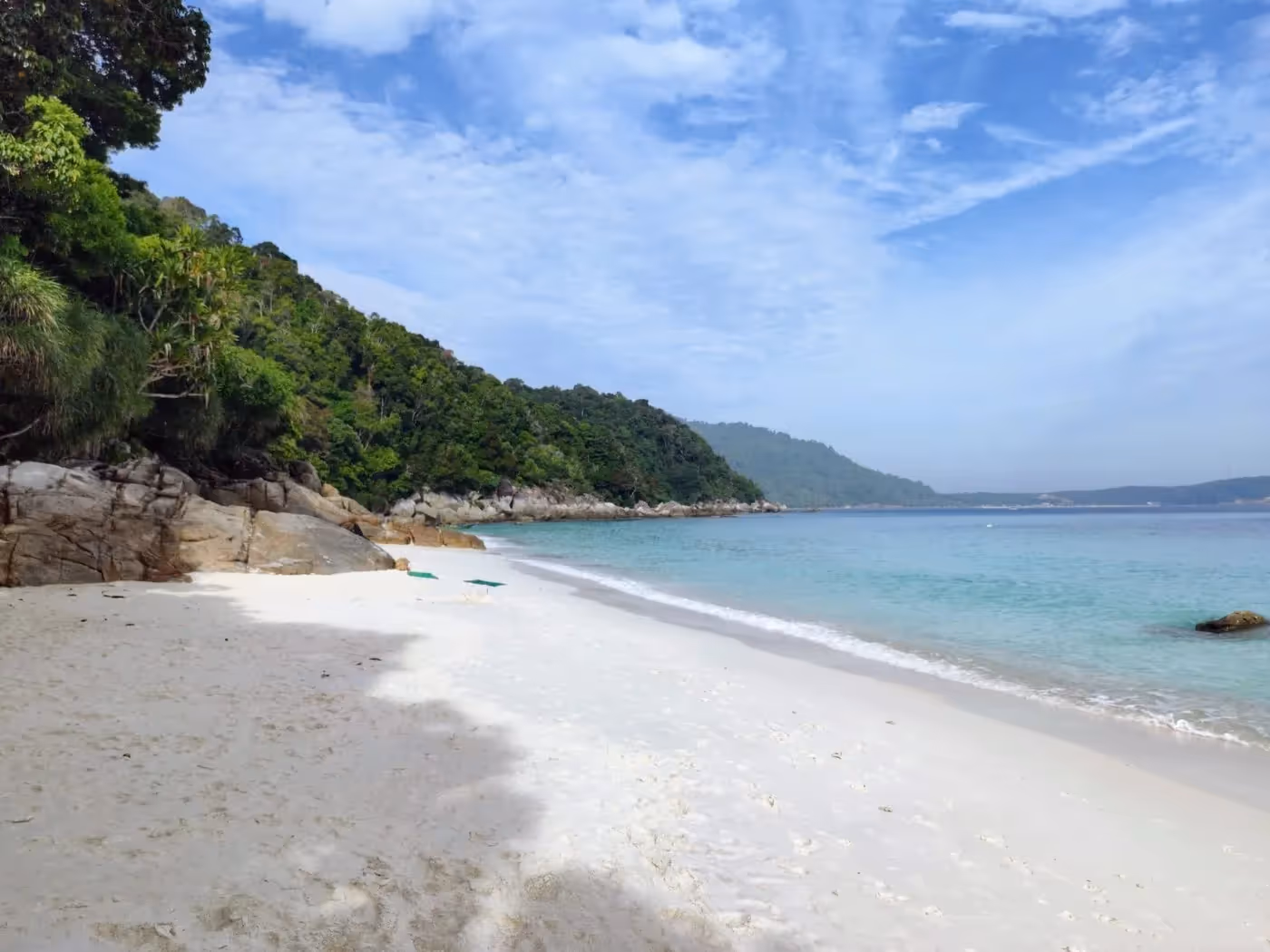 Plage de Turtle Beach sur Pulau Besar avec sable blanc et jungle tropicale en arrière-plan.