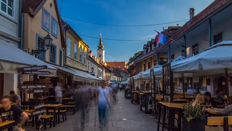 rue animée de Zagreb en soirée avec cafés et vue sur une église baroque