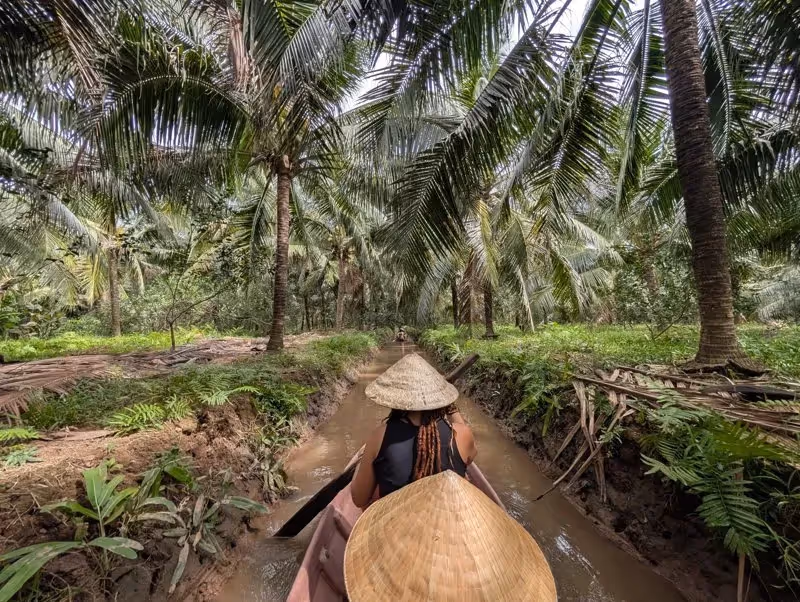 Promenade en barque traditionnelle à travers les canaux bordés de palmiers dans la région de Bến Tre, au sud du Vietnam.