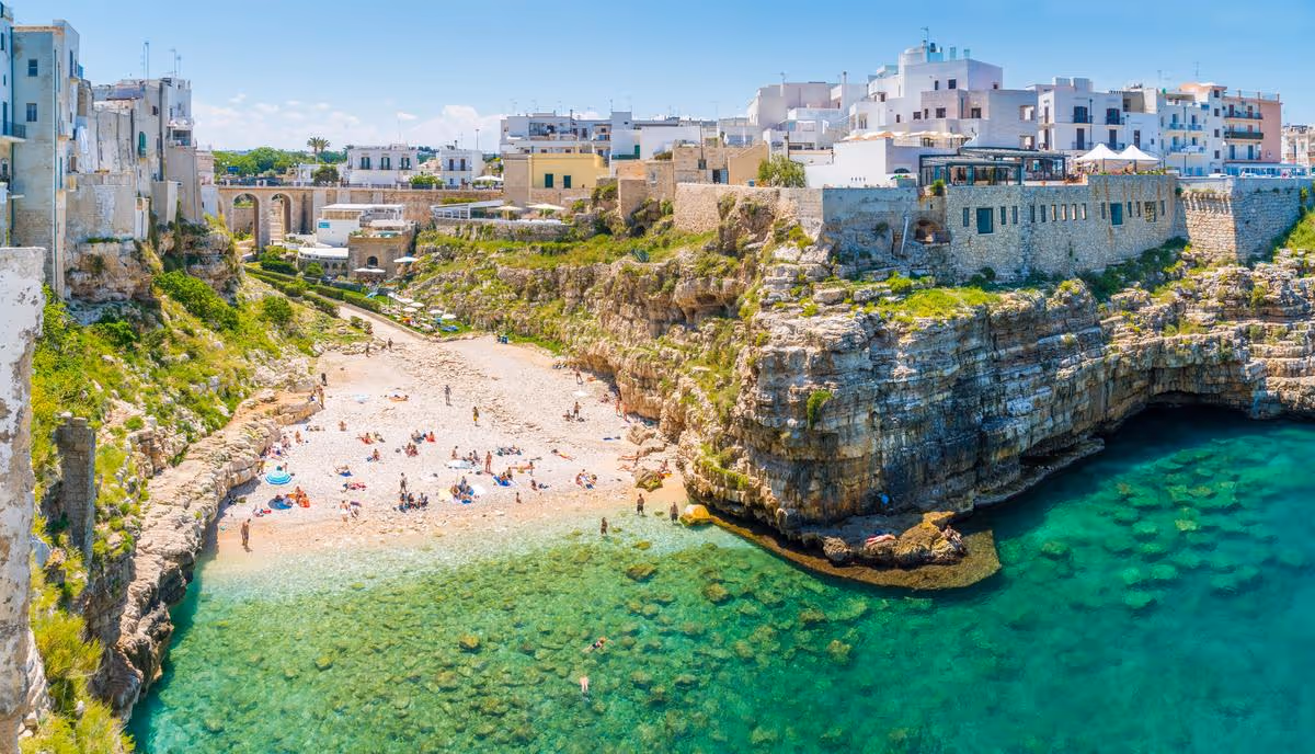 Plage de galets et eaux turquoise entourées de falaises à Polignano a Mare, dans les Pouilles, Italie.