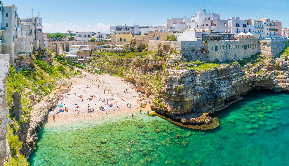 Plage de galets et eaux turquoise entourées de falaises à Polignano a Mare, dans les Pouilles, Italie.