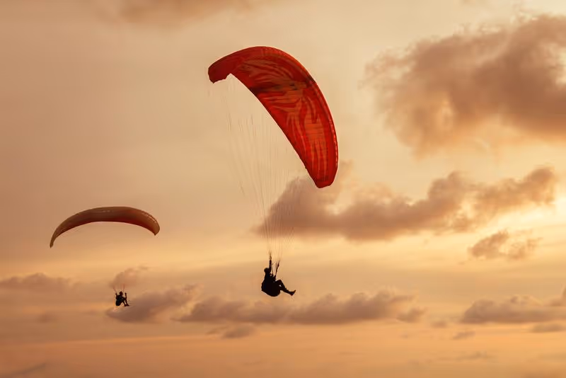 Deux parapentistes volant au coucher du soleil au-dessus du désert péruvien.