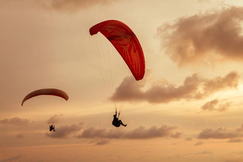 Deux parapentistes volant au coucher du soleil au-dessus du désert péruvien.