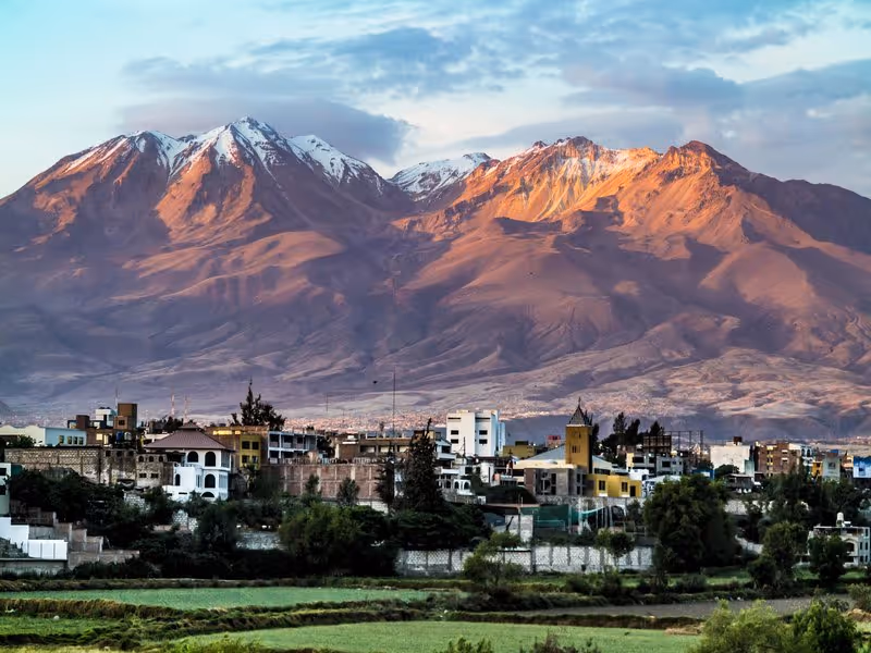 Vue panoramique du volcan Chachani avec ses sommets enneigés dominant la ville d’Arequipa au coucher du soleil.