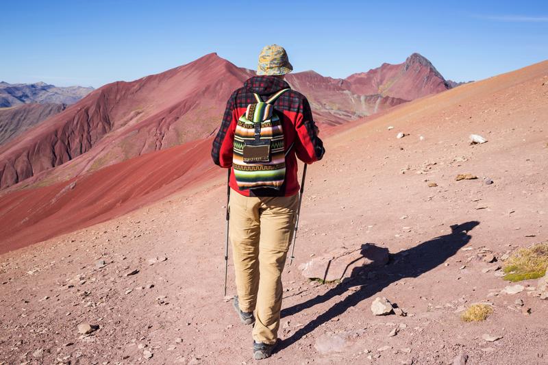 Randonneur sur les sentiers de Vinicunca au Pérou avec les montagnes rouges en arrière-plan