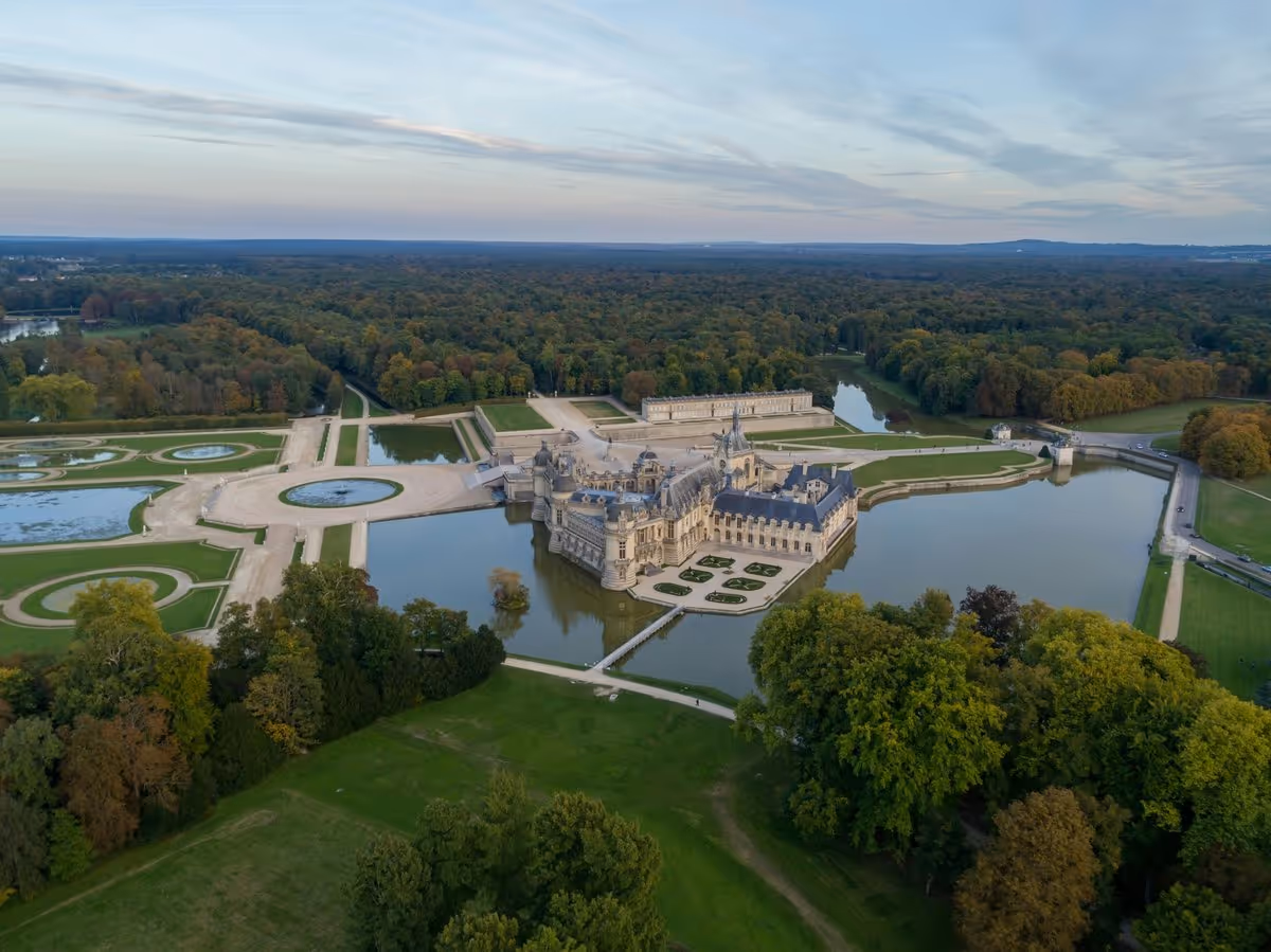 Vue aérienne du château de Chantilly et de ses jardins à la française entourés d’eau dans l’Oise.