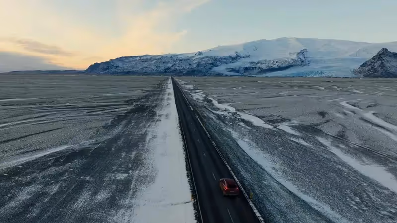 Route enneigée en Islande avec une voiture et des montagnes en arrière-plan