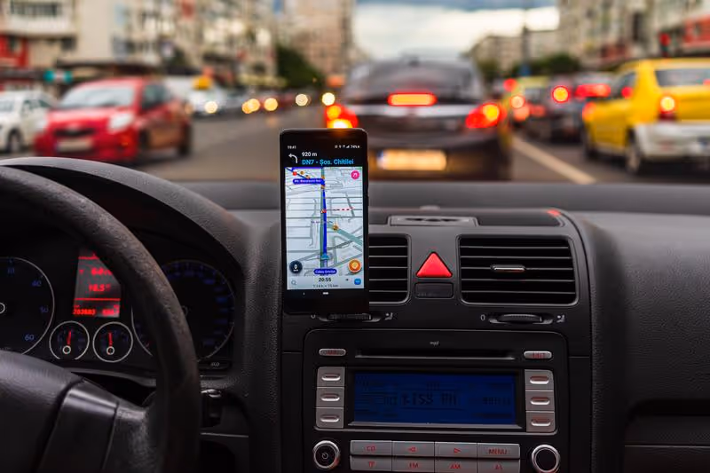Application Waze affichée sur un smartphone fixé dans une voiture, utilisée pour la navigation GPS en temps réel.