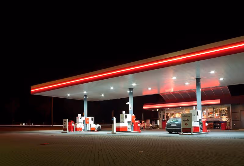 Station-service éclairée la nuit, arrêt incontournable lors d’un road trip pour faire le plein de carburant.