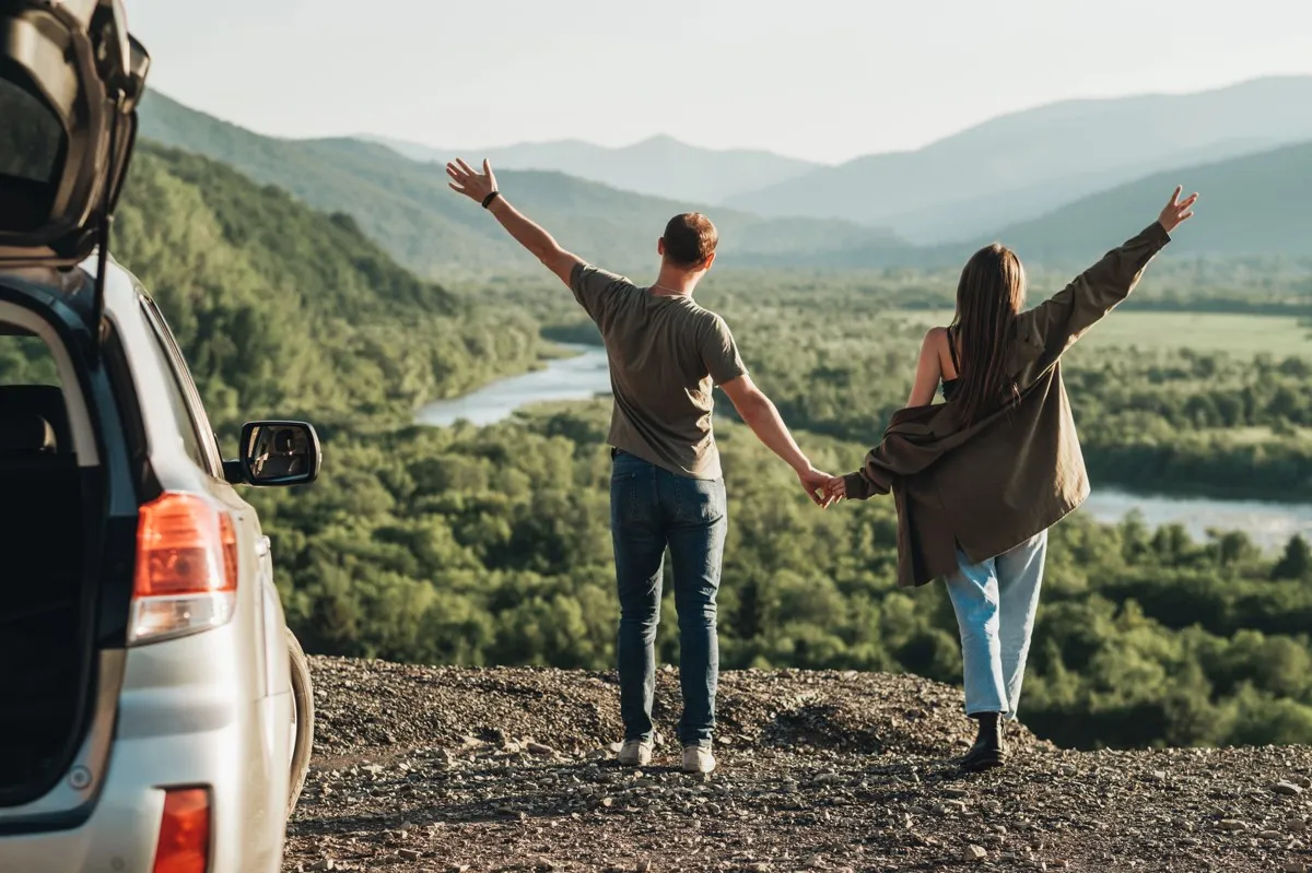 Couple profitant d'une vue panoramique sur les montagnes lors d'un road trip en voiture pas cher