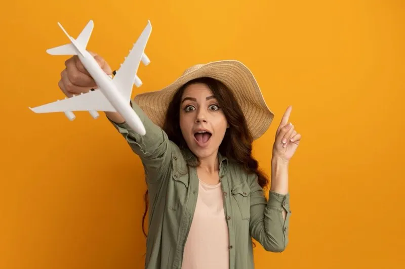 Voyageuse souriante tenant un avion miniature, symbolisant la passion du voyage et l’envie d’évasion responsable.