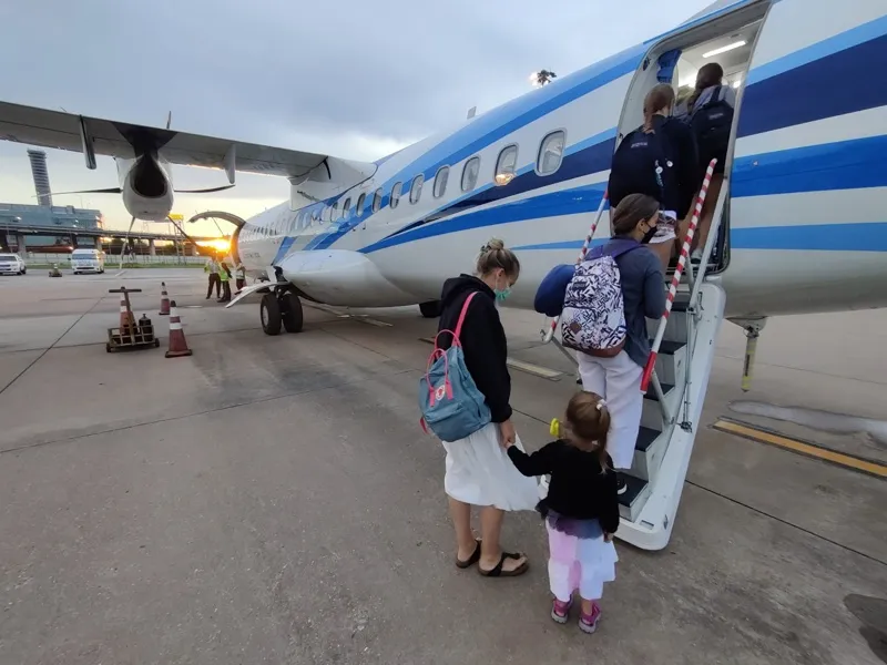 Maud et Anna montant à bord d’un avion au coucher du soleil sur le tarmac.